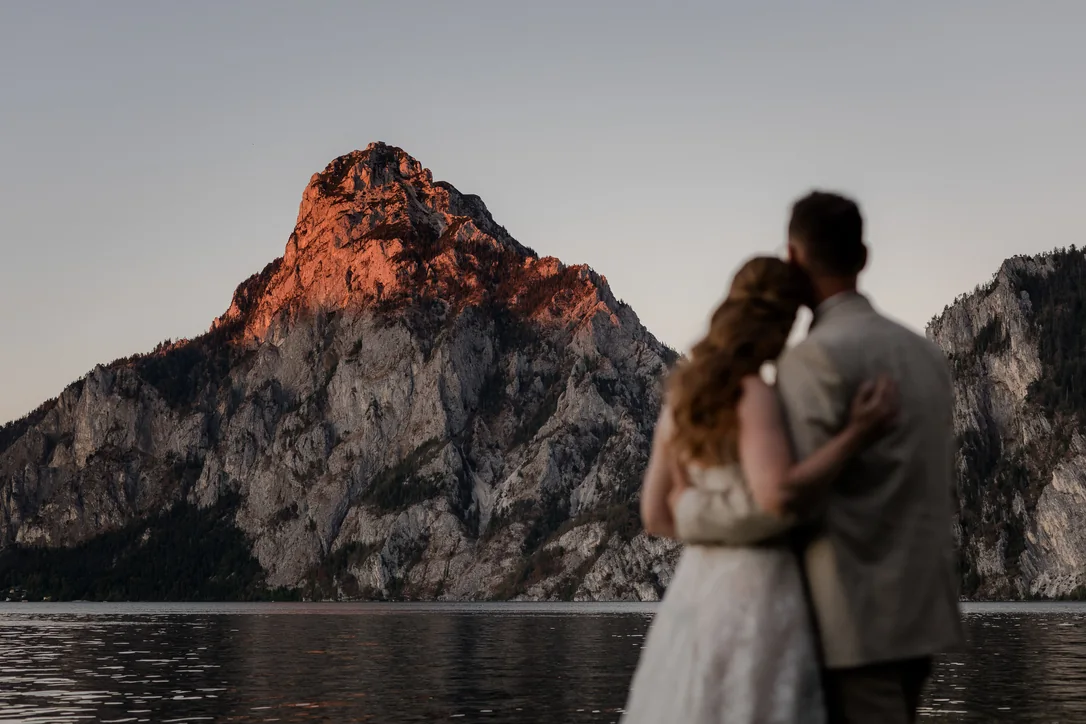 Brautpaar vor dem Traunsee und den rot leuchtenden Bergen im Abendlicht des Salzkammerguts