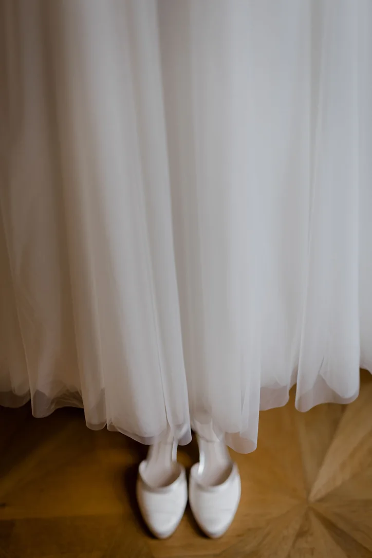 Weiße Brautschuhe unter dem Brautkleid beim Getting Ready im Schloss Wolfsberg