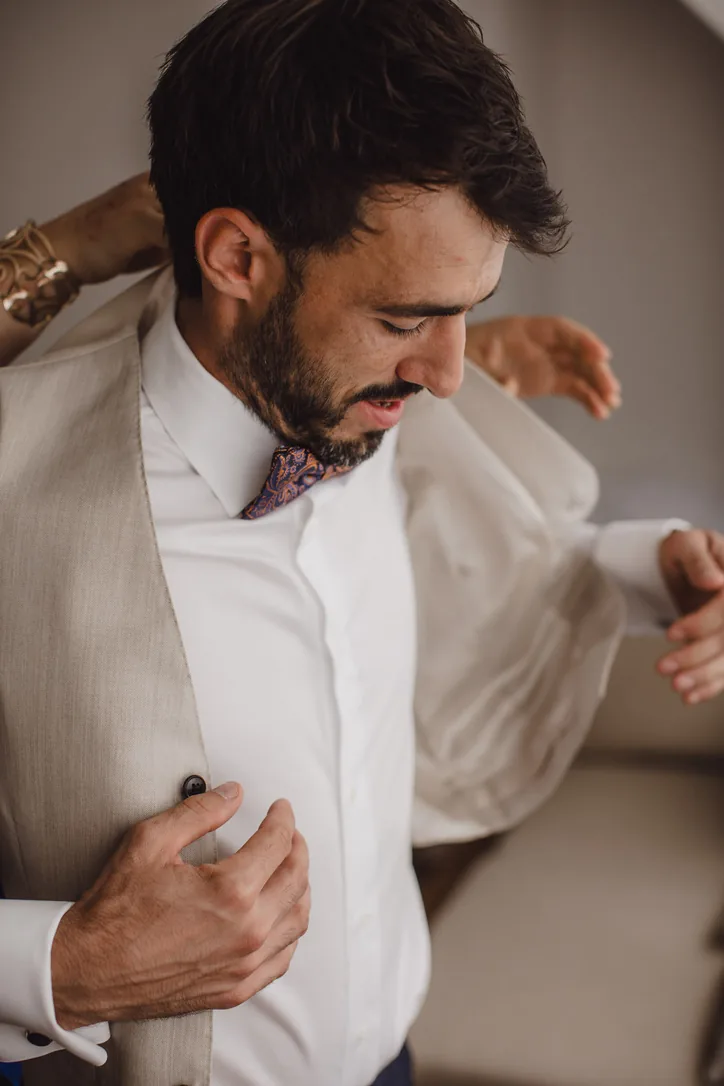 Bräutigam zieht beim Getting Ready vor der Hochzeit am Schloss sein dunkles Sakko an