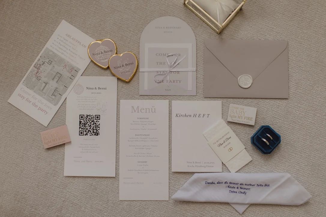 Flatlay mit Eheringen, Papeterie, Menükarte und kleinen Hochzeitsdetails in hellen Naturtönen