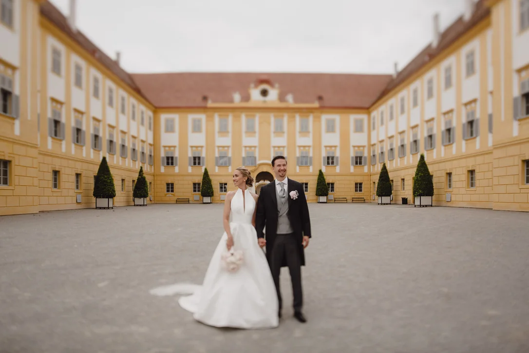Brautpaar steht gemeinsam im großen Innenhof eines barocken Schlosses in Niederösterreich